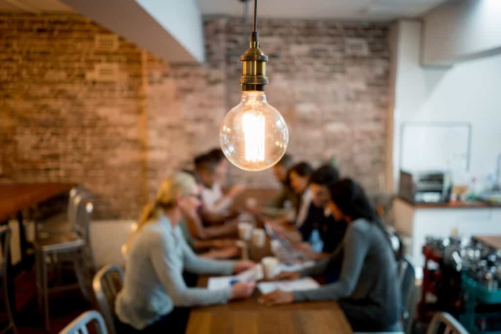 Group of business people brainstorming at a creative office and a light bulb in the foreground